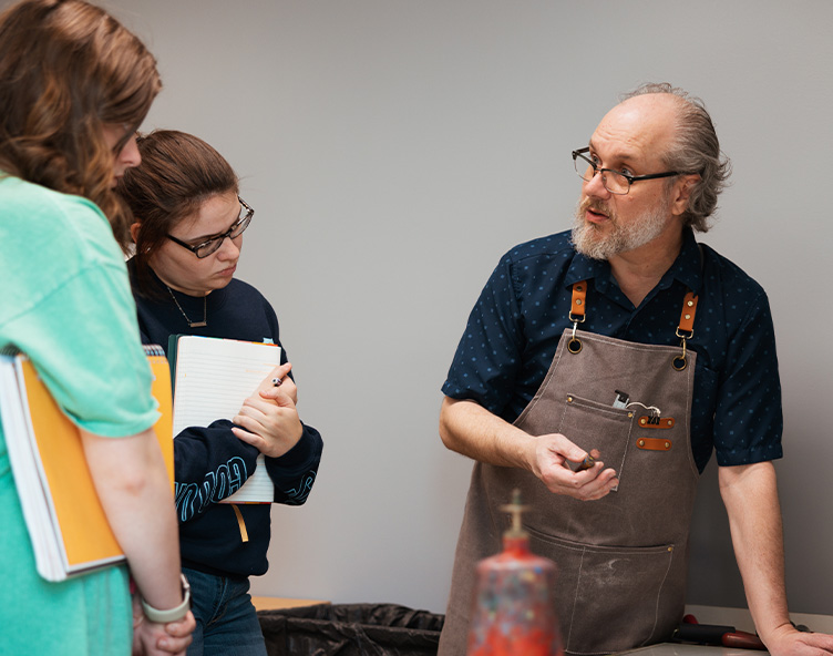 teacher demonstrates printmaking techniques to students
