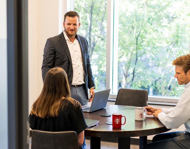man talking to clients at a table in an office