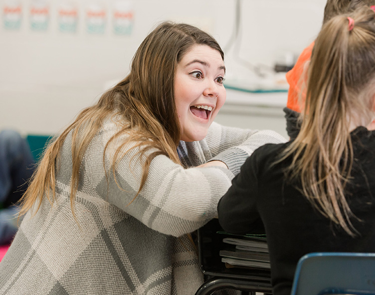 teacher helping a young student in a classroom