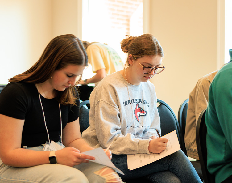 students writing on paper in a classroom