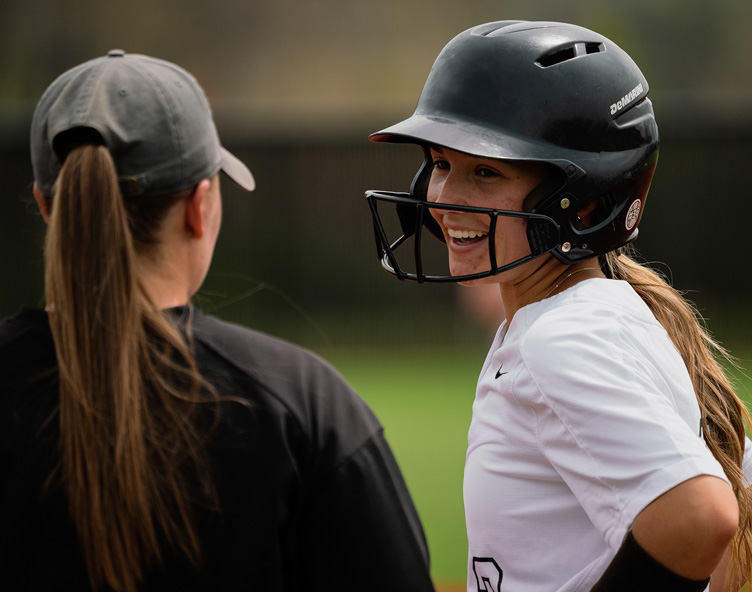 two girls chatting on softball field