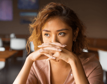 Asian female student concerned look with folded hands over mouth